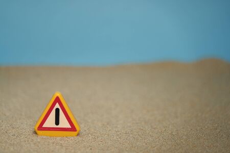 Attention signal on beach sand and blue sky background and with spaces around the motif to be able to put texts. Perfect for backgroundsの写真素材