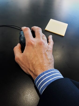 Executive hand handling the mouse with yellow paperの写真素材