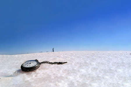 Abandoned watch on the snow in the winter on a background of blue sky