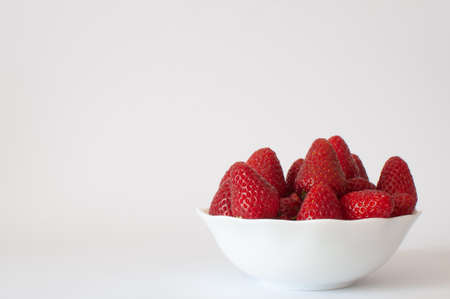 Strawberries, organic and delicious red strawberries in white bowl with copy space on left. Isolated on white background, selective focus.の写真素材