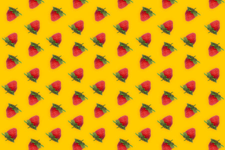 Sweet and tasty strawberries isolated on yellow background like banana. Red berry fruits patternの写真素材