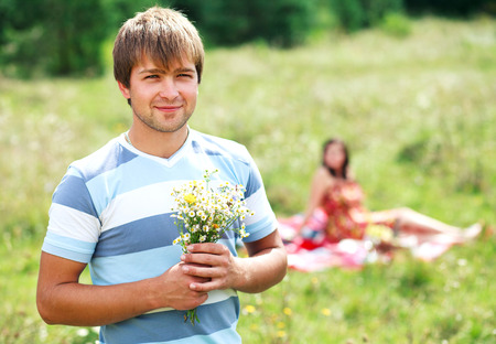 young handsome guy gives his girlfriend a bouquet of daisiesの写真素材