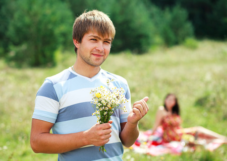 young handsome guy gives his girlfriend a bouquet of daisiesの写真素材