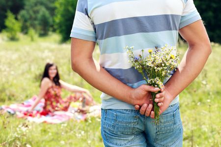 young handsome guy gives his girlfriend a bouquet of daisiesの写真素材
