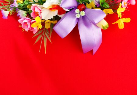 artificial flower arrangement on a red background with space for greetingsの写真素材