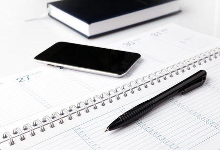 notepad with pen and electronic notebook on a white backgroundの写真素材