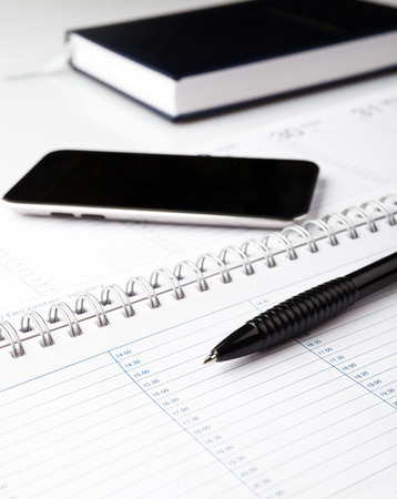 notepad with pen and electronic notebook on a white backgroundの写真素材