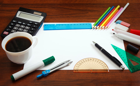Desk with sheet of paper and stationery objects seen from above