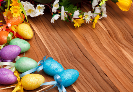 Easter flower arrangement and colorful eggs on a wooden surface with space for textの写真素材
