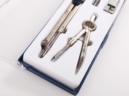 Pair of drawing compasses set on a white backgroundの写真素材