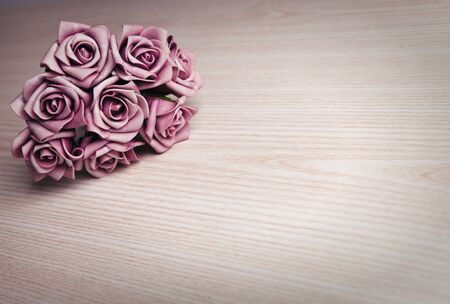 bouquet of purple roses on wooden surface with space for textの写真素材