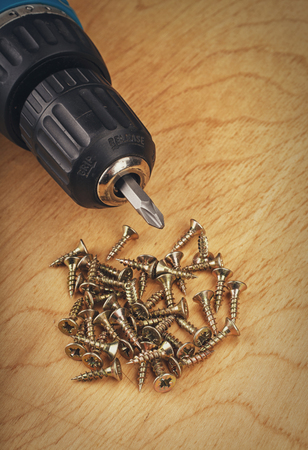 drill and large screws on a wood backgroundの写真素材
