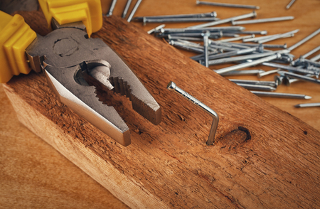 pliers  hammer and nail on a wooden boardの写真素材