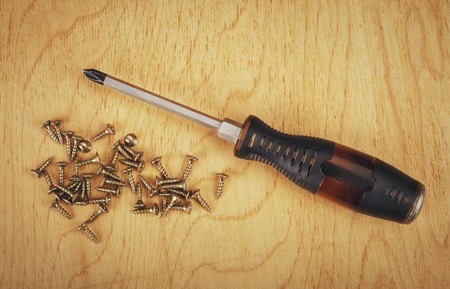 Screws and screwdriver on wooden background.の写真素材