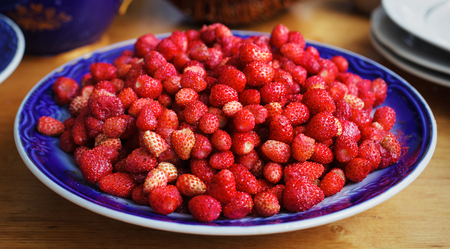 Fresh ripe wild strawberries in a bowl on wooden tableの写真素材