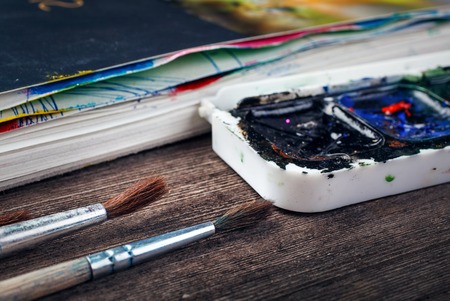 Paints and brushes on a wooden background closeupの写真素材