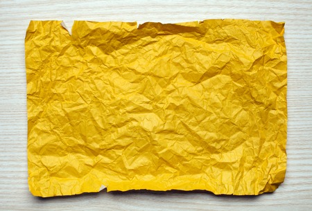 Crumpled  yellow paper card on wooden background, place for texの写真素材
