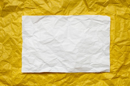 Crumpled  white paper card on yellow background, place for tex
