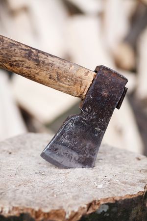Axe stuck in a stump on a background of chopped firewoodの写真素材