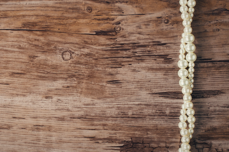 White pearl necklace on a wooden background,  place for textの写真素材