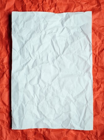 Crumpled  white paper card on red background, place for texの写真素材