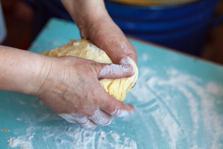 Woman's hands knead dough blue on a table
