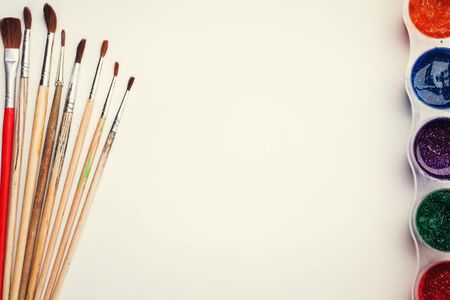 Frame pictures wits copyspace composition painting tools on white sheet of paper on wooden boardの写真素材