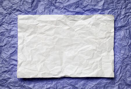 Crumpled  white paper card on violet  background, place for texの写真素材