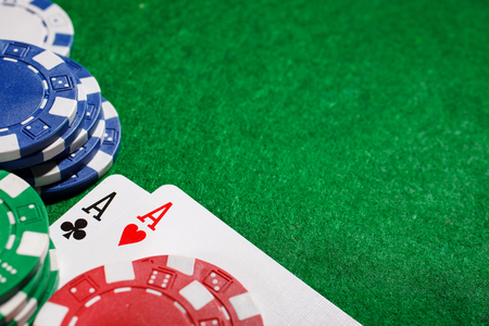 Stack of chips and two aces on the table on the green baize - poker game concept