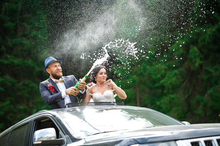 just married couple Bourne uncork champagne in hatch carの写真素材