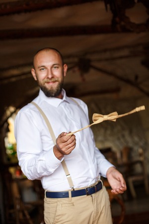bearded man twisting bow tie in hand. wedding time