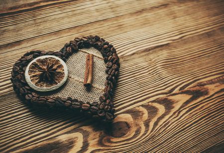 Decorative heart from coffee beans with cinnamon on wooden backgroundの写真素材