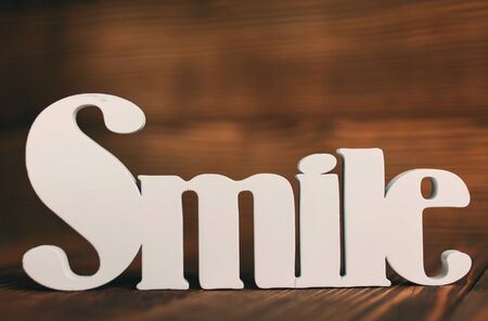 word, smile and motivation concept - smile text on wooden background with space for textの写真素材