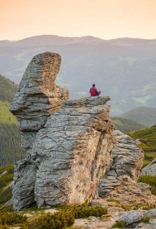 Man Sitting in the Lotus Position on the Rock Above mountain and Meditating at the Early Morning. Yoga Outdoorの写真素材