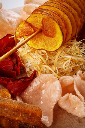 Set snacks to beer. Potato chips, chicken wings, basturma and cheese on a wooden board.の写真素材