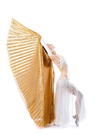 Beautiful young girl in a white suit oriental dance with big golden wings isolated on white backgroundの写真素材