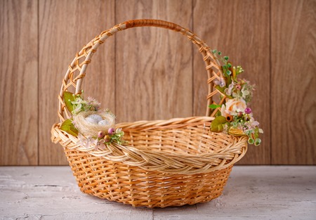 Beautiful decorative basket with flowers to celebrate Easter on wooden board