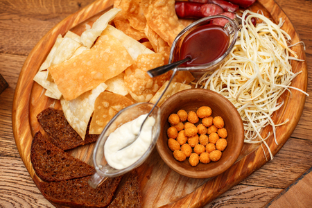 Tasty snacks for beer. Hot hunting sausages, cheese, chips, white and red sauce on the board.の写真素材