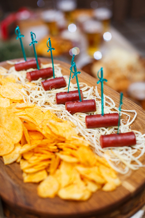 Delicious snacks for beer. Hot hunting sausages on the cheese next to the chipsの写真素材