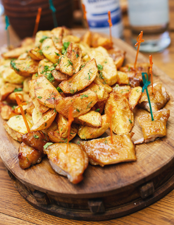 Delicious snacks for beer. Hot chicken with baked potato on the boardの写真素材