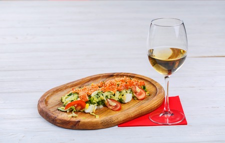 Summer dishes from: red fish, eggs, cucumbers, tomatoes, salad and Peking cabbage next to a glass of white wine. Fine dining at the restaurantの写真素材