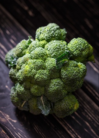 Broccoli with leaves. Relief broccoli on a dark wooden backgroundの写真素材