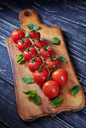 Branch of cherry tomatoes on a wooden boardの写真素材