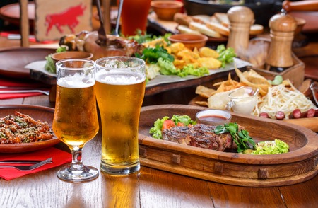 Beer table in the pub. Hot steak with sauce and vegetables.の写真素材