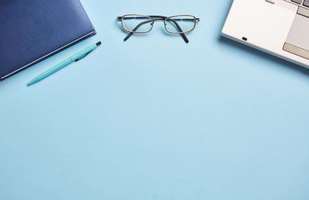 On a blue background notebook, glasses and stationery.の写真素材