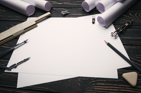 On a wooden table are drawings, compasses, pencil, elastic, ruler and sharpener.