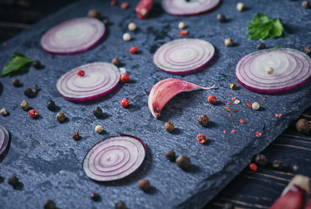 Onions, garlic, pepper peas and greens on a gray boardの写真素材
