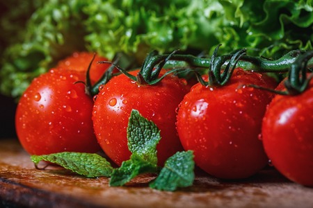 On a wooden board, small tomatoes with mintの写真素材