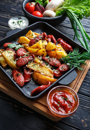 Concept promotional flyer. Baked potatoes along with vegetables and sauces. On a black wooden backgroundの写真素材