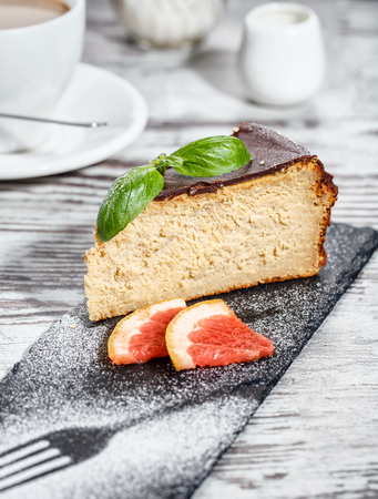 Concept promotional flyer. Cheese cake with chocolate icing along with two slices of grapefruit. On a light backgroundの写真素材